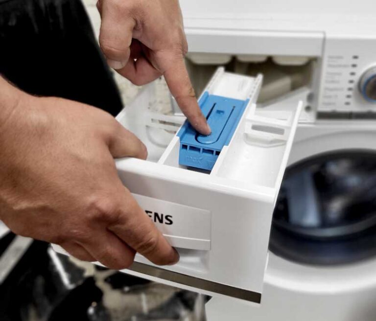 Techniker zieht die Einspülkammer eines Waschtrockners heraus
