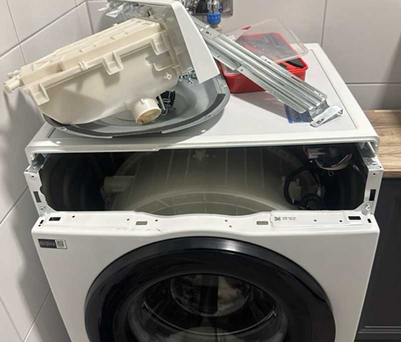 Wäschetrockner mit ausgebautem Bedienelement und Ersatzteilen obendrauf