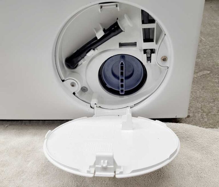 Nahaufnahme einer geöffneten Serviceklappe mit Flusensieb einer Waschmaschine