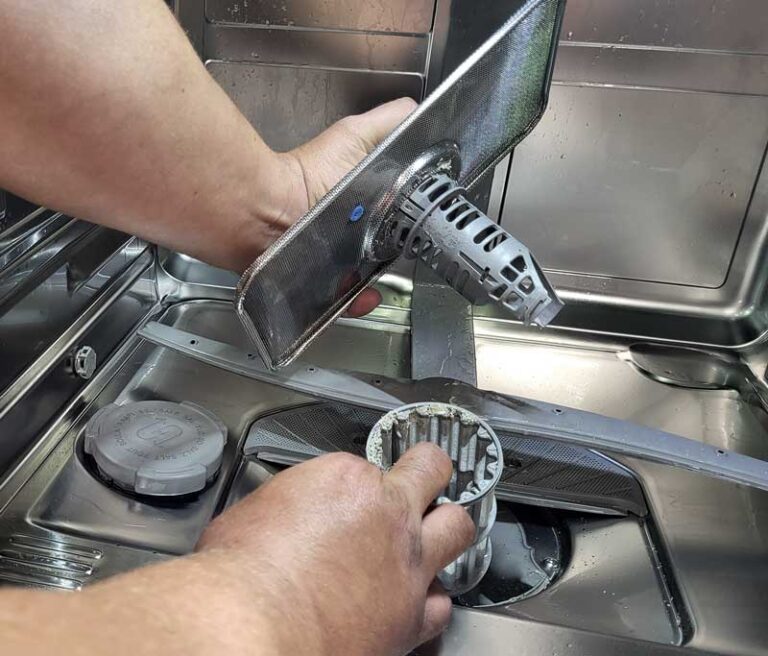 Zwei Hände die in einem Geschirrspüler den Filter ausbauen