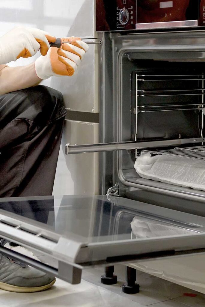 Techniker schraubt an einem Einbaubackofen