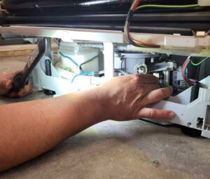 Eine Hand hält eine Lampe eine andere Hand prüft ein aufgeschraubtes Gerät