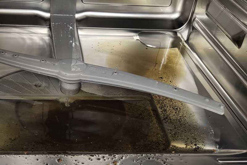 Boden eines Geschirrspülers mit dreckigem Spülwasser