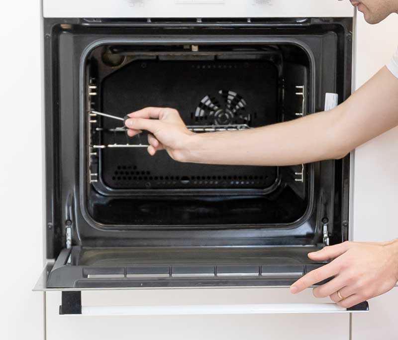 Techniker schraubt an einem Backofen