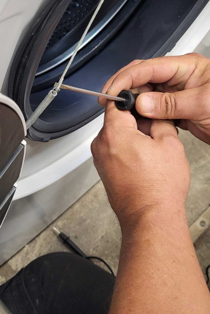 Zwei Hände mit Schraubenzieher an einer Waschmaschine