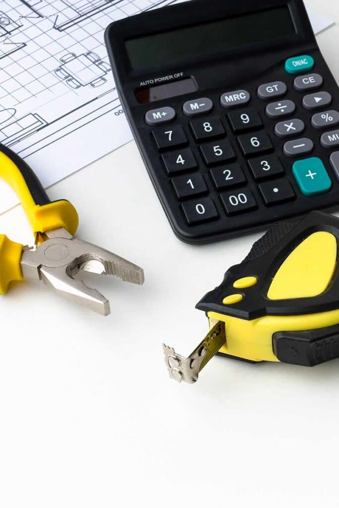 Tisch auf dem Taschenrechner, Zange und Metermaß liegen