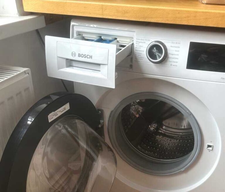 Waschmaschine mit geöffneter Tür und Dosierkasten